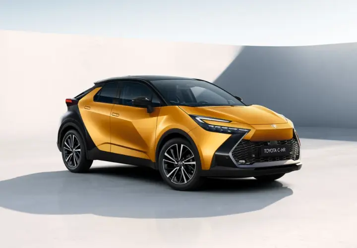 Nowa Toyota C-HR w kolorze złoto-czarnym, stylowa toyota hybryda, prezentuje się dynamicznie na tle minimalistycznej architektury.