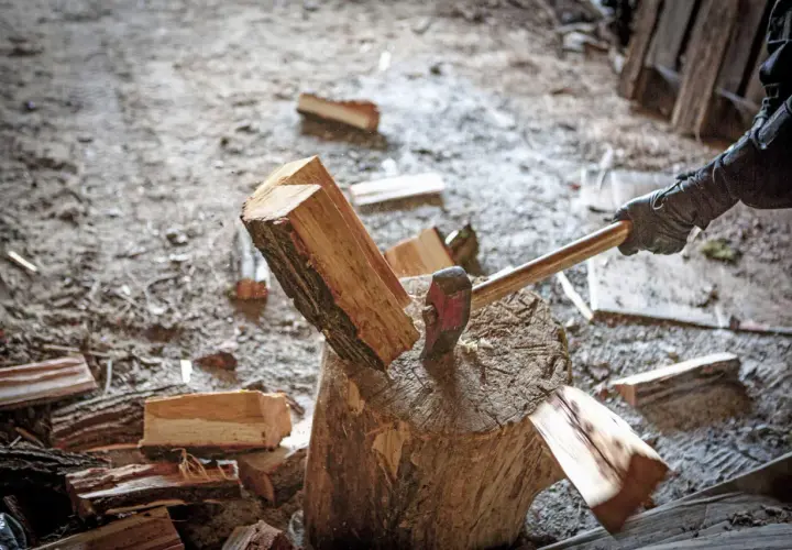 Axt spaltet Holzscheit. Informiere dich über aktuelle brennholz preise bayern, um dein Zuhause warm zu halten.