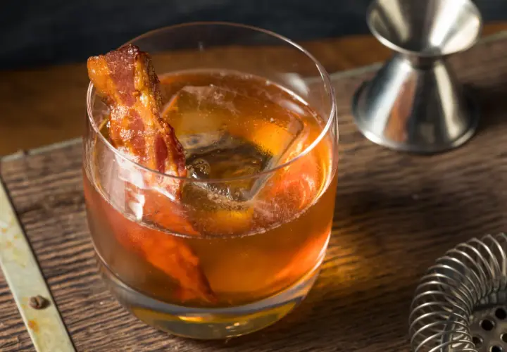 Whisky z boczkiem, czyli jak zrobić infuzowaną whisky z boczkiem (fat washing) techniką barmańską. Drink z lodem i plasterkiem boczku.