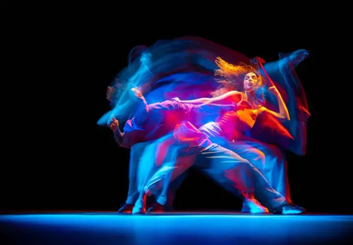 Tancerze w ruchu, tworzący świetlne smugi. Zastanawiasz się, ile zarabia choreograf tańca?