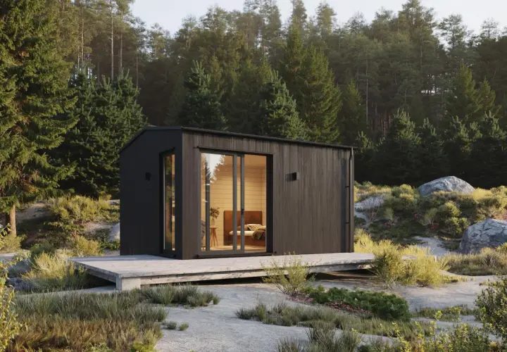 Modern friggebod med stora fönster, omgiven av skog och sten. Drömmen om att bygga friggebod blir verklighet.