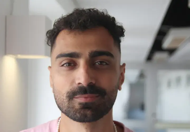 Alexander Abdallah, en ung man med lockigt mörkt hår och skägg, tittar rakt in i kameran.