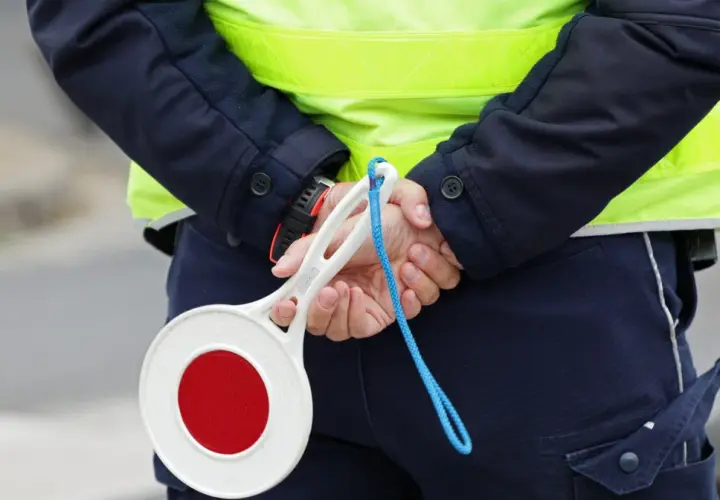 Policjant w kamizelce odblaskowej trzyma znak stop. Zastanawiasz się, ile km można jechać na autostradzie?