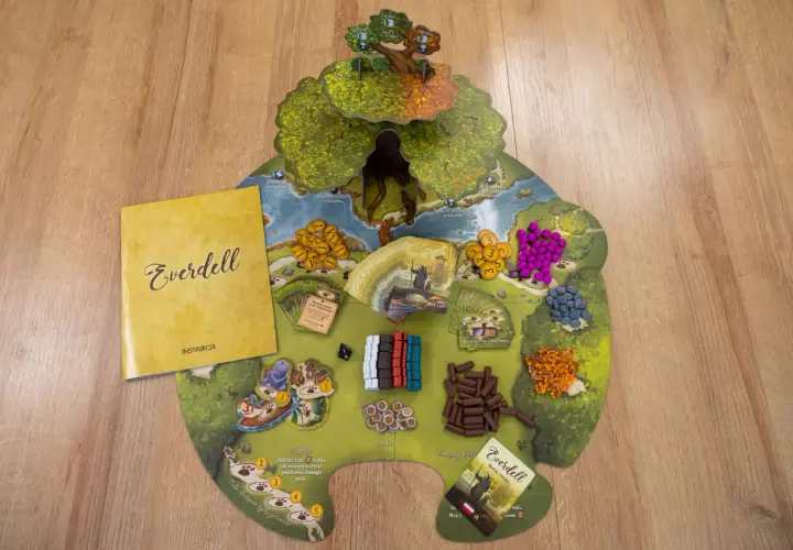 Plansza do gry Everdell z instrukcją i komponentami. Kolorowe zasoby i karty czekają na graczy.