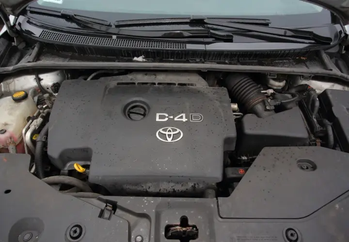 Silnik Toyota Avensis 2.0 D4D, widok z góry. Pokrywa silnika z logo Toyoty i oznaczeniem D4D.