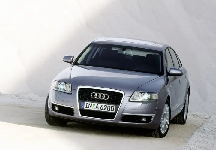 Szary Audi C6 z tablicą rejestracyjną IN A 6200 stoi na piaszczystym podłożu.