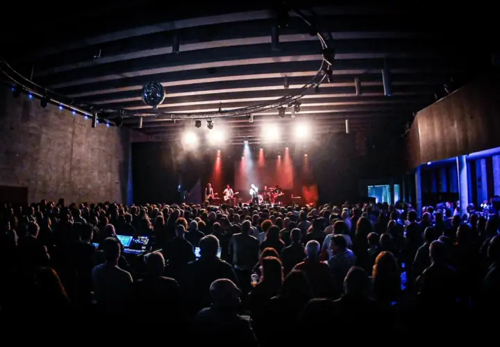 Un concierto en un **escenario Santander** lleno de gente, con luces rojas y blancas iluminando a la banda.
