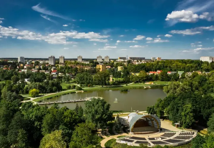 Amfiteatr i staw w Ostrowcu Świętokrzyskim, zielone tereny i budynki mieszkalne tworzą malowniczy krajobraz. To jedne z wielu ostrowiec świętokrzyski atrakcje.