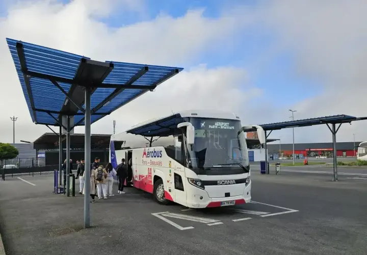 Autobus Aerobus z napisem "Paris-Beauvais" czeka na pasażerów pod niebieskim zadaszeniem.