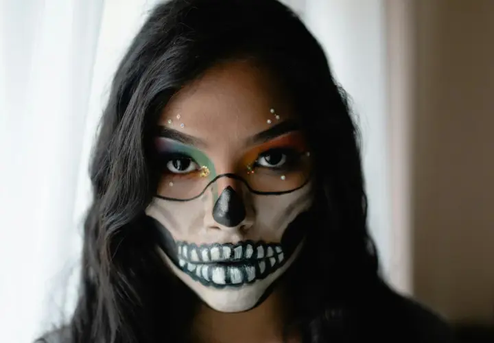 Makijaż na Halloween w stylu sugar skull: czarne kontury czaszki, kolorowe cienie do powiek i błyszczące dżety.