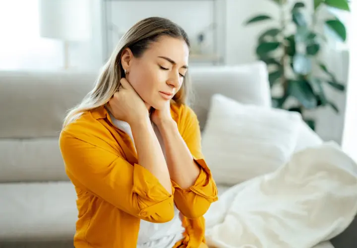Donna con occhi chiusi e mani sul collo, soffre di dolori muscolari diffusi.