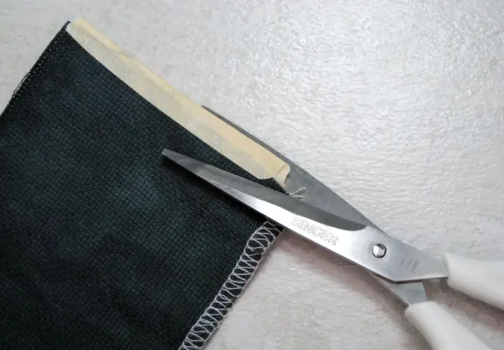 Singer scissors cut dark green corduroy fabric. The edge is serged, showing that corduroy does not fray easily.