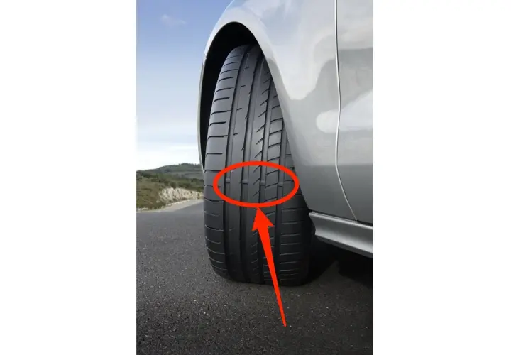 Indicador de desgaste en un neumático. La flecha roja señala cómo saber si las ruedas están gastadas, mostrando el nivel de la banda de rodadura.