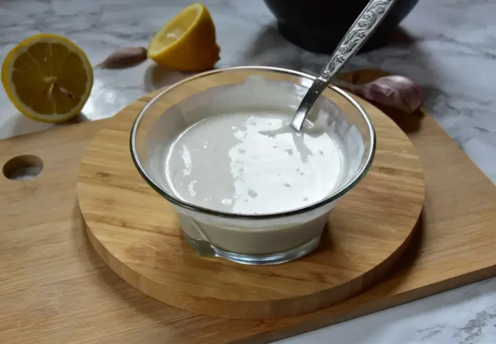 Kremowe aioli w miseczce, obok cytryna i czosnek. Idealne do dipów i sosów.
