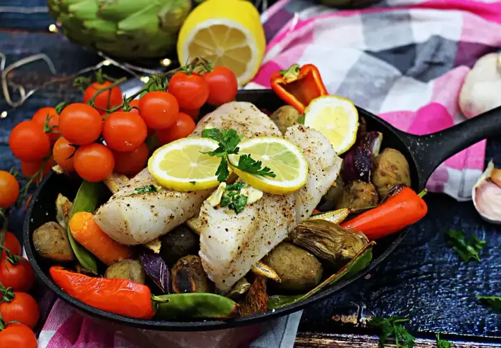 Pyszny halibut ryba pieczony z warzywami i cytryną na patelni.