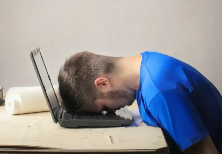 Frustrierter Mann mit Kopf auf Laptop. Er sucht nach einem Musterbrief für den Widerruf einer Abo-Falle.