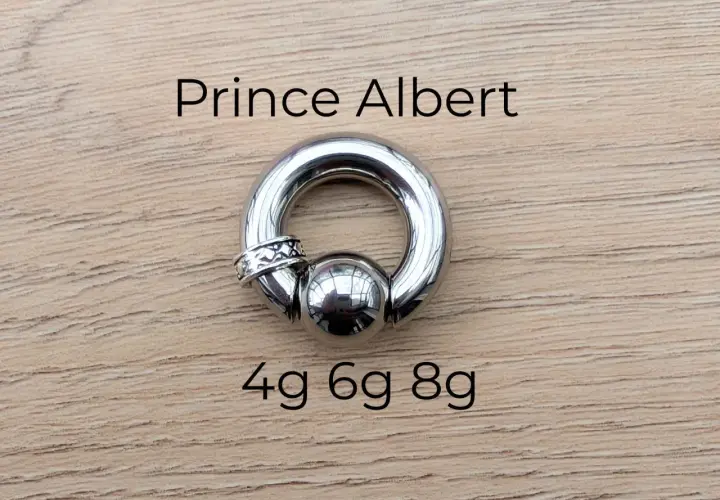Stalowy kolczyk typu prince albert, z kulką i ozdobnym pierścieniem, rozmiary 4g, 6g, 8g.