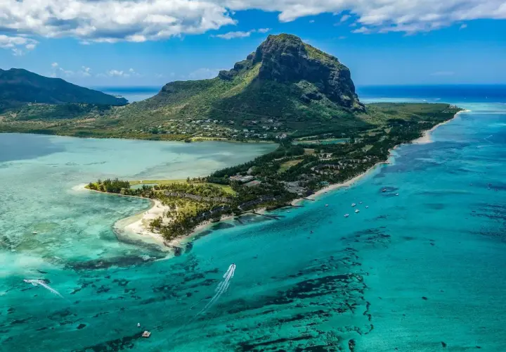 Widok z lotu ptaka na górzysty brzeg Mauritiusa z turkusową wodą i łodziami.