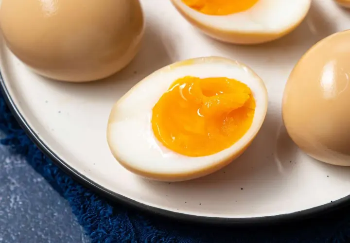 A plate of perfectly cooked onsen eggs, some whole and some halved to reveal their creamy, golden yolks.