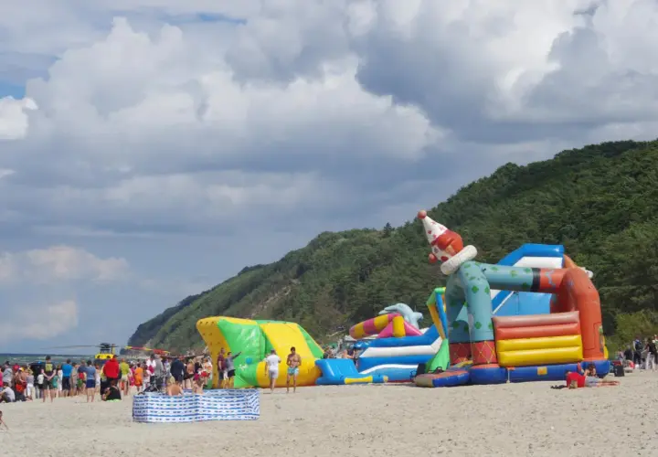 Kolorowe dmuchańce na plaży w Międzyzdrojach to świetne atrakcje dla dzieci. Wesoły klaun zaprasza do zabawy.