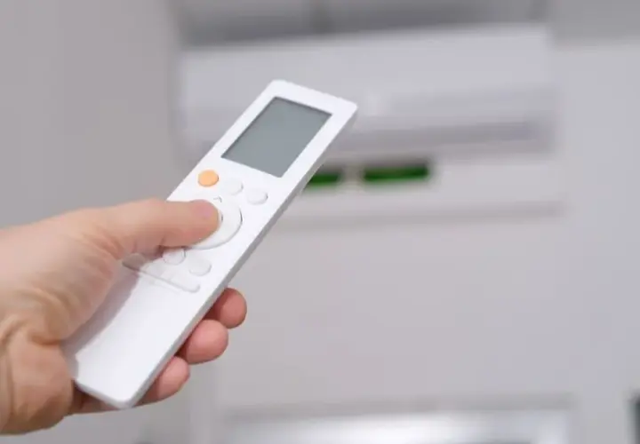Mano sujetando control remoto para aprender como poner aire acondicionado en frio.