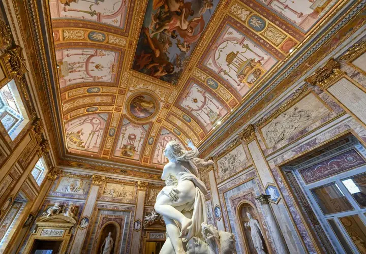 Sculpture saisissante dans une salle ornée de fresques au **jardin de la Villa Borghese**. Le plafond est un chef-d'œuvre baroque.