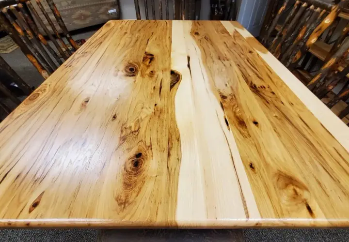 A rustic dining table crafted from the prettiest wood, showcasing natural grain patterns and knots. Chairs with twig-like legs surround it.