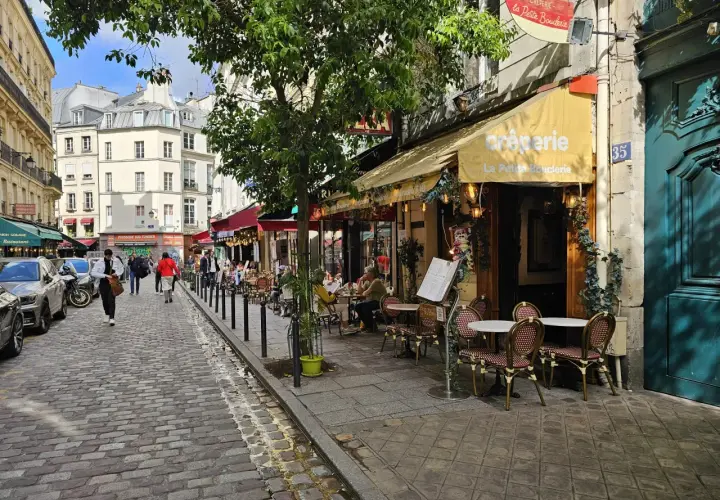 Ulica w dzielnicy łacińskiej Paryża z kawiarnią "La Petite Boulangerie" i brukowanym chodnikiem.