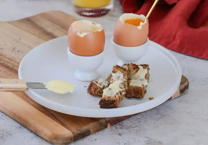 Deux oeufs à la coque, prêts à être dégustés avec des mouillettes de pain beurrées. Un petit-déjeuner simple et réconfortant.