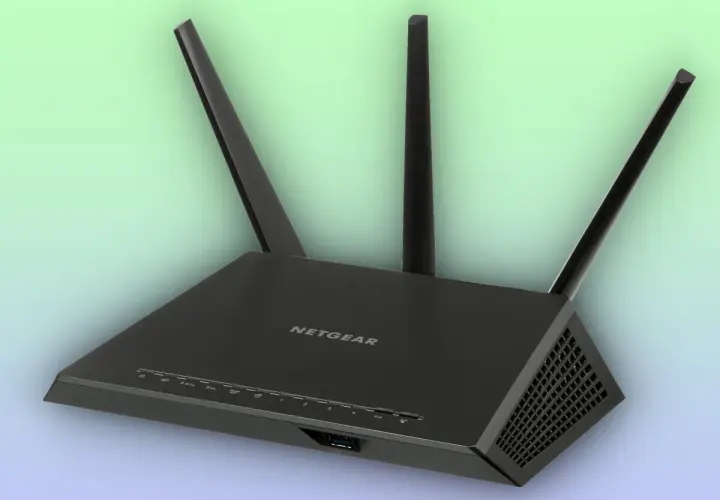 Un enrutador Netgear negro con tres antenas, esencial para tu conexión a internet.