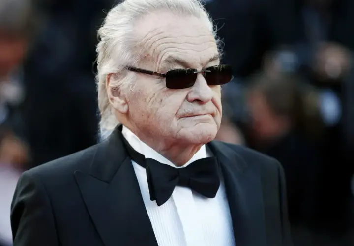 Jerzy Skolimowski w smokingu i okularach przeciwsłonecznych, ikona polskiego kina.