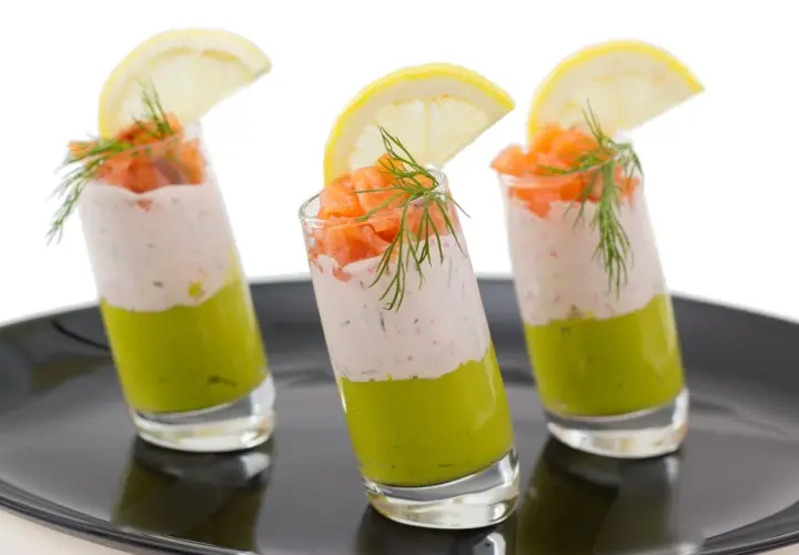 Trois verrines charcuterie : avocat, crème et saumon fumé, garnies d'aneth et d'une tranche de citron.