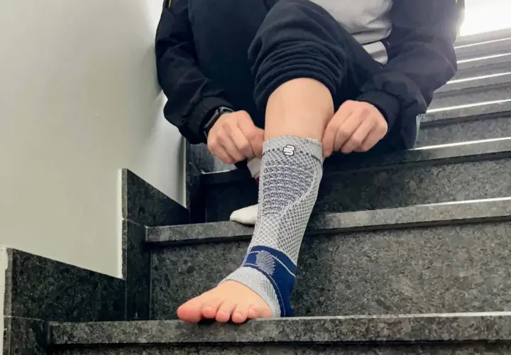 Person zieht eine Bandage am Fuß an, die bei einem Achillessehnenriss Schuh-Schmerzen helfen soll.