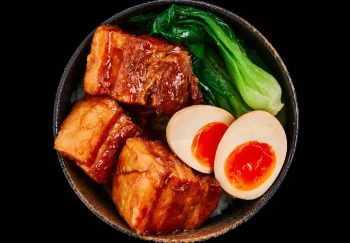 A bowl of Japanese pork belly with rice, bok choy, and a soft-boiled egg.