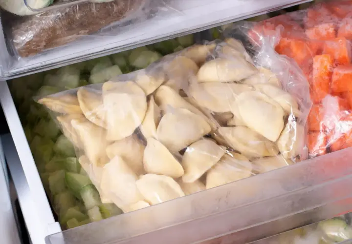 Jak mrozic domowe pierogi? W zamrażarce leżą woreczki z pierogami, mrożonymi warzywami i innymi produktami.