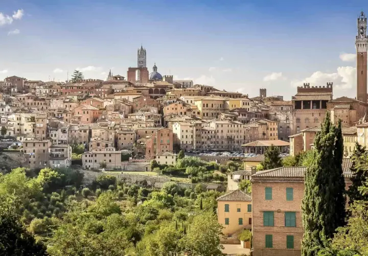 A panoramic view of Siena's historic skyline, a beautiful destination on the journey from Lucca to Siena. The Torre del Mangia tower stands tall amidst terracotta rooftops.