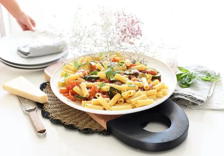 Plato de pasta con verduras salteadas, calabacín, tomate y albahaca, con queso parmesano rallado.