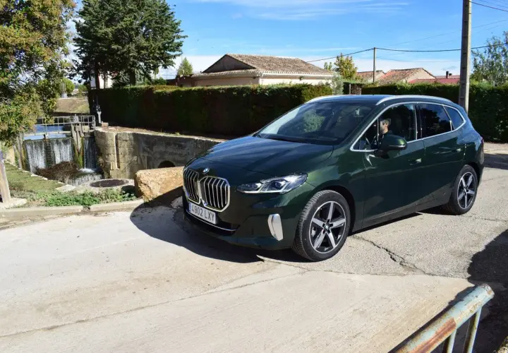 Un BMW Serie 2 Active Tourer verde oscuro aparcado cerca de una esclusa de agua. ¿Problemas con el coche o solo una parada escénica?