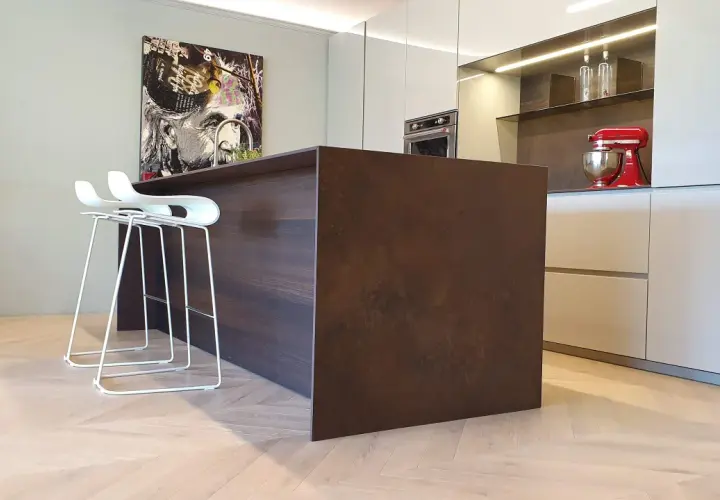 Moderno montaggio cucina con isola centrale in legno scuro, sgabelli bianchi e quadro artistico.