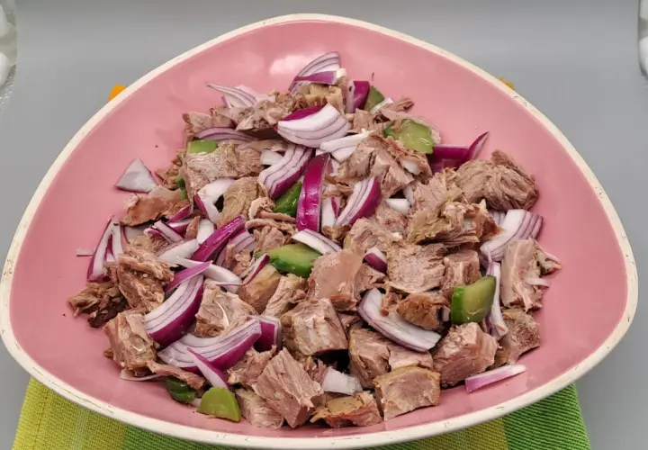 Salade de viandes froides, un plat savoureux avec des morceaux de viande, des oignons rouges et des avocats, servi dans un bol rose.