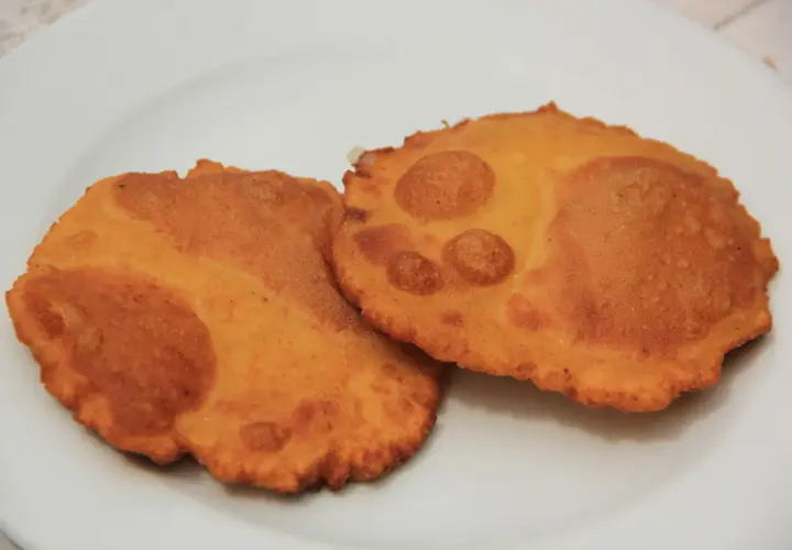 Dos tortos asturianos dorados y crujientes sobre un plato blanco.