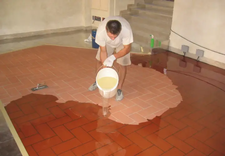 Uomo versa resina per coprire piastrelle cucina, creando una superficie lucida e moderna.