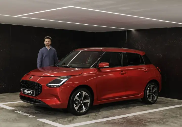 Hombre posando junto a un Suzuki Swift rojo brillante, listo para su prueba.