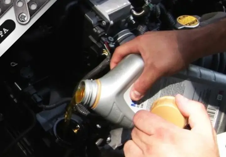 Mano che versa olio motore nel vano del motore. Il tappo giallo indica dove si mette l'olio motore.