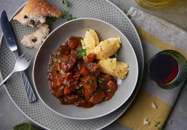 Herzhaftes Spezzatino di manzo mit cremigem Polenta, dazu ein Glas Rotwein und rustikales Brot.