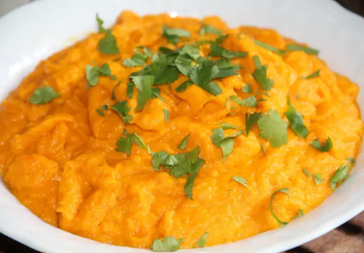 Purée de carotte onctueuse, garnie de feuilles de coriandre fraîche. Un délice orangé et savoureux.