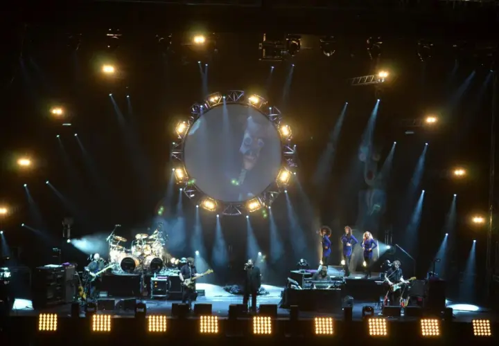 Koncert Australian Pink Floyd z okrągłym ekranem i wokalistami na scenie.