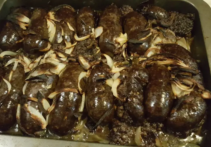 Kaszanka pieczona w piekarniku z cebulą, apetycznie przyrumieniona, gotowa do podania.