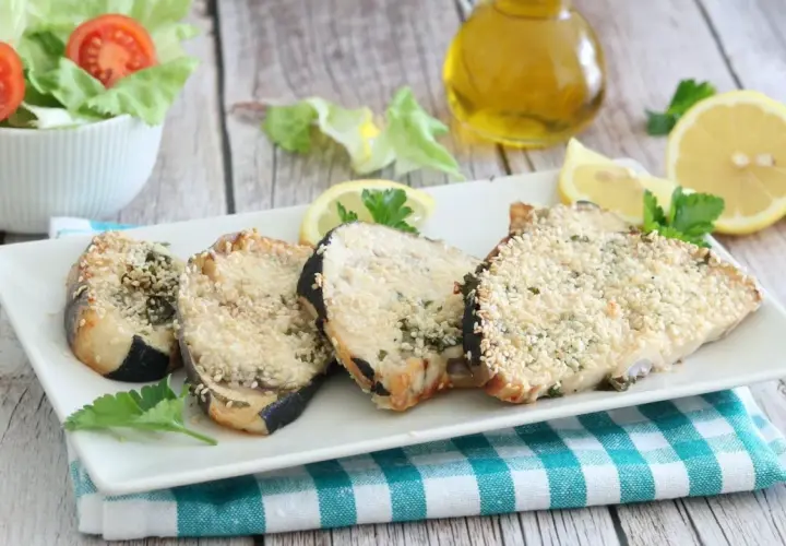 Fette di pesce spada impanate con sesamo, cotte in friggitrice ad aria, servite con limone e insalata.