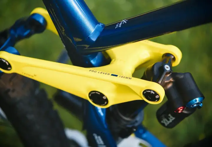 Żółte ramię korby z napisem "PRO LEVER 180MM" na tle niebieskiej ramy roweru.